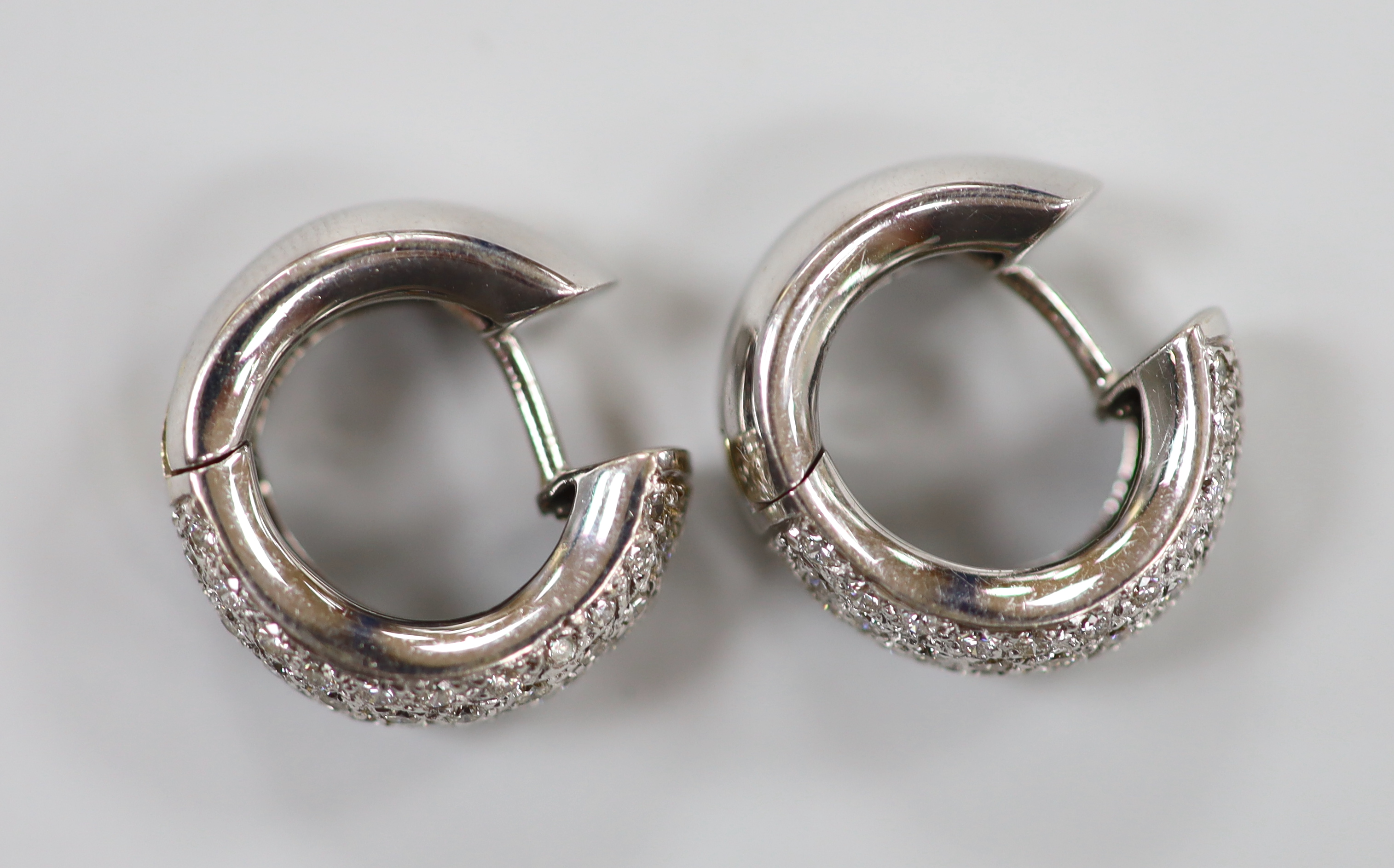 A modern pair of 750 white metal and pave set diamond chip half hoop earrings, 15mm, gross weight 7.4 grams.